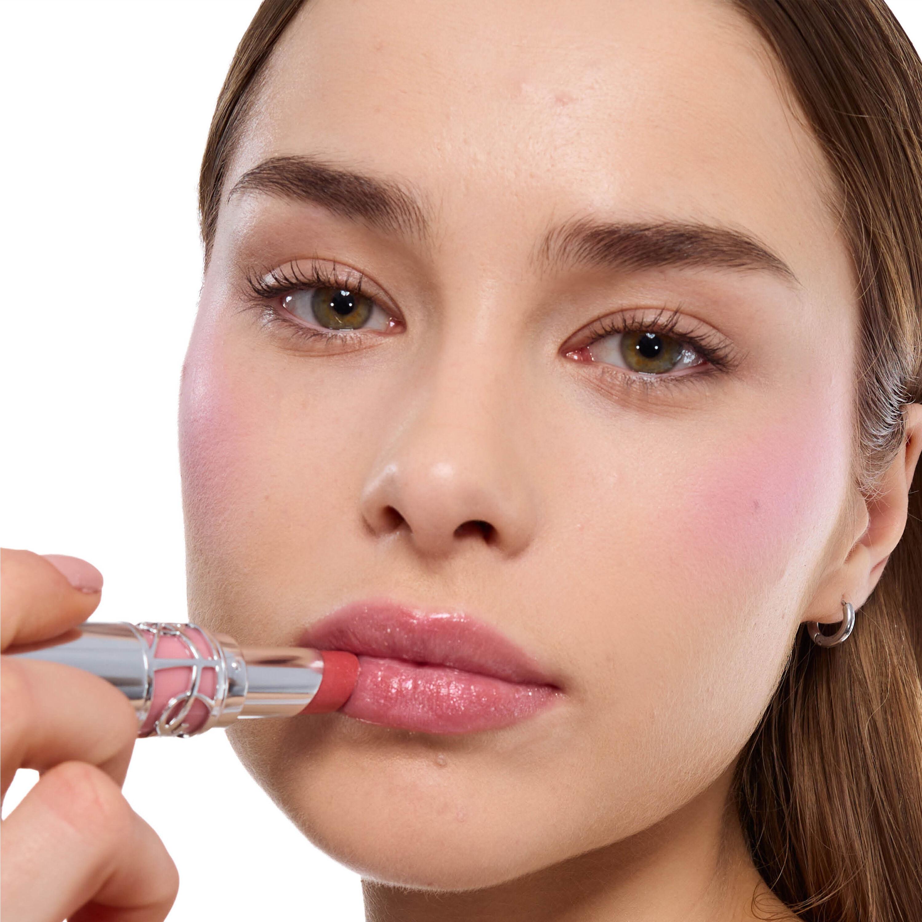 Musu, dark skin, holds YSL LOVESHINE Lipstick, shimmery pink.
Cheeks show blush.